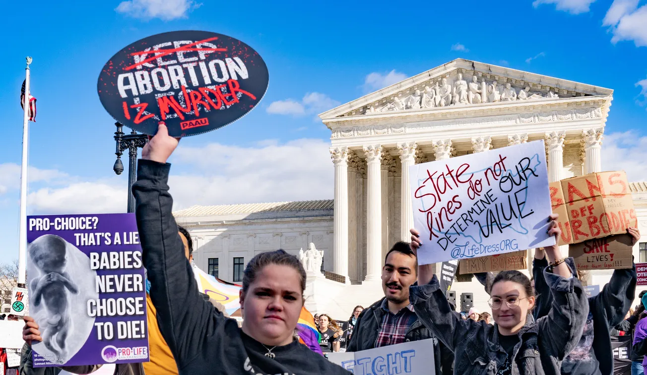 Photo of anti-abortion demonstrators outside the US Supreme Court holding signs that read: "abortion is murder" and "pro-choice? that's a lie babies never choose to die."